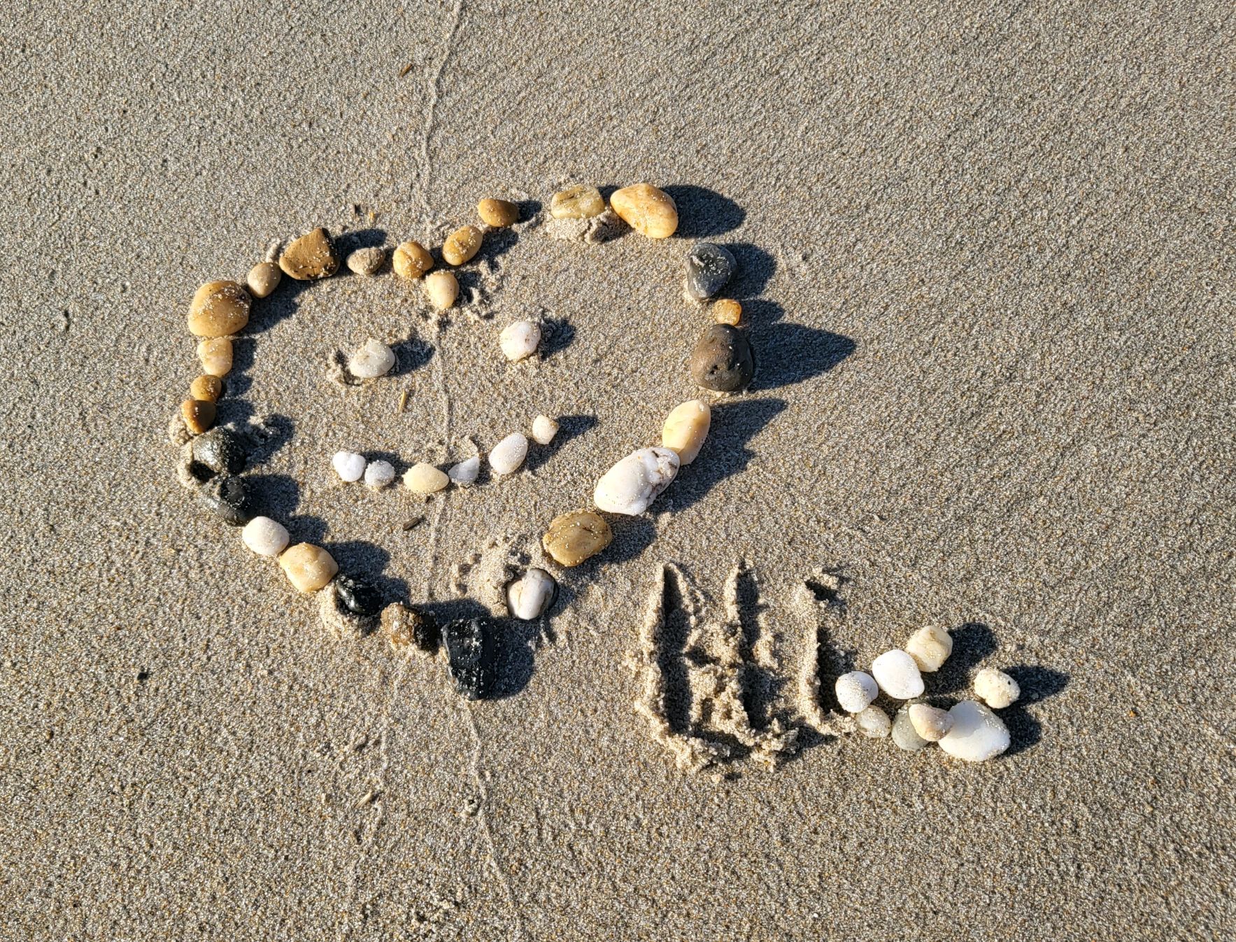 Stones shaped as a heart with Hi spelled out in the sand