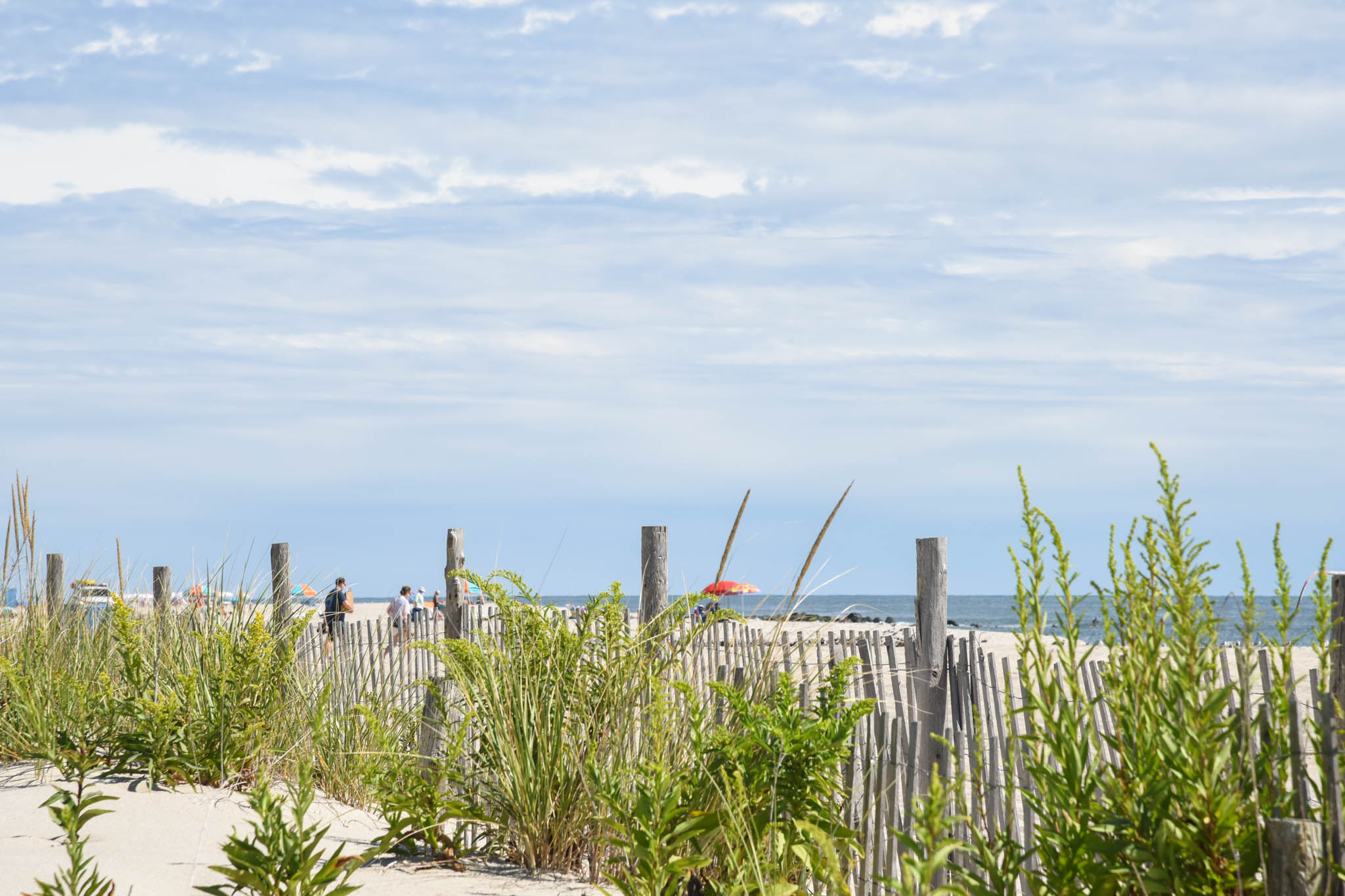 Looking through the dunes as People are walking to the beach on a September Day