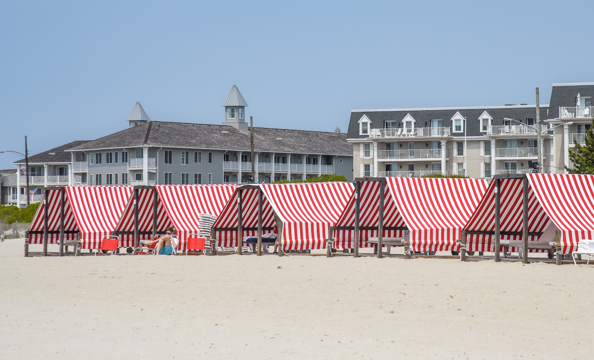 A guy reading on the beach in front of Congress Halls Cabanas.