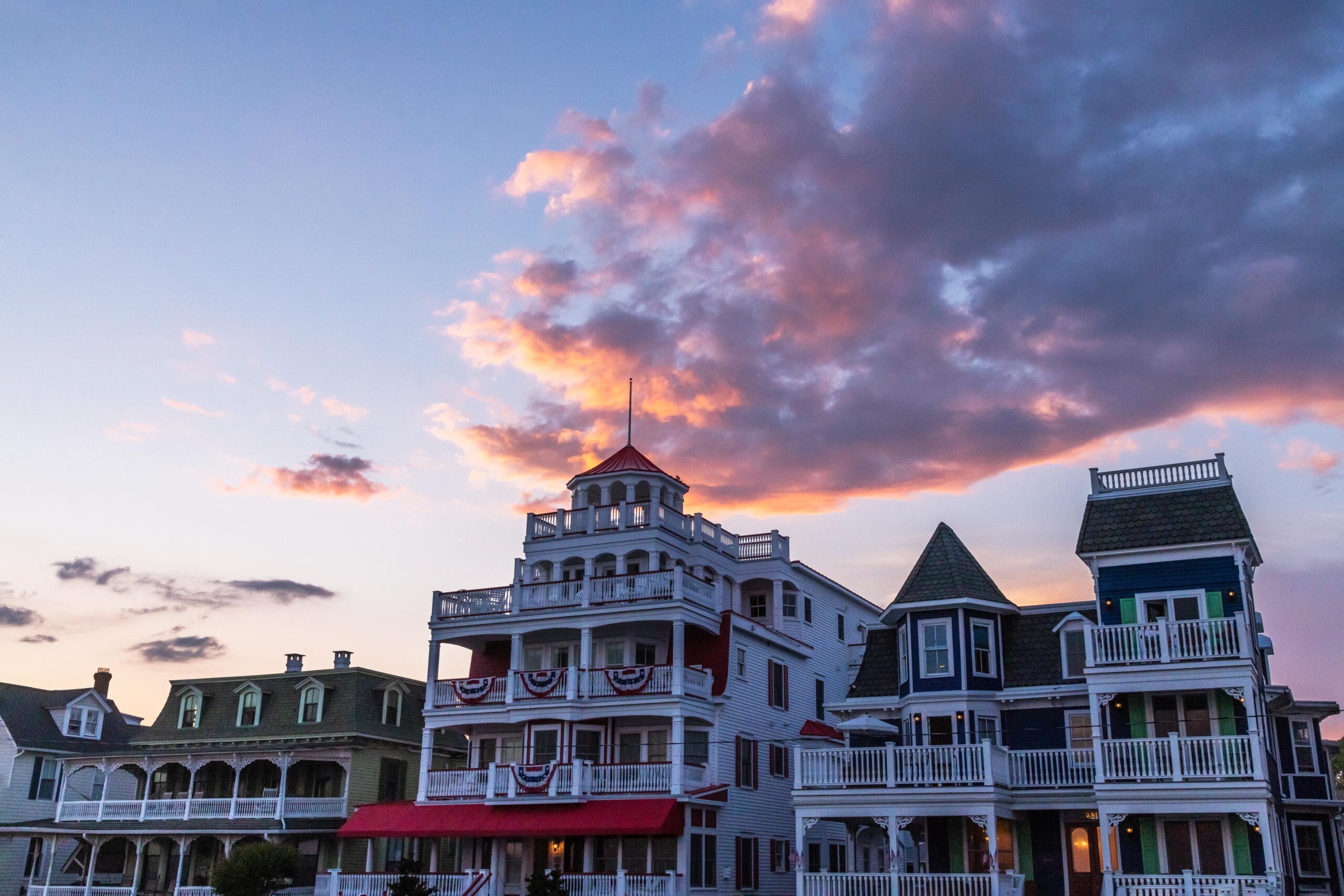 Victorian houses on Beach Avenue with a pink, purple, and blue cloud in the sky at sunset