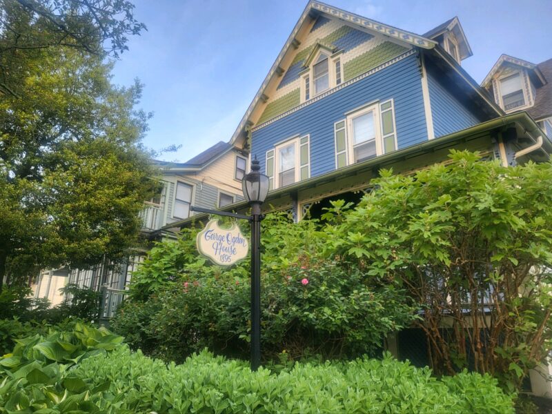 A three-story blue house with gingerbread trim