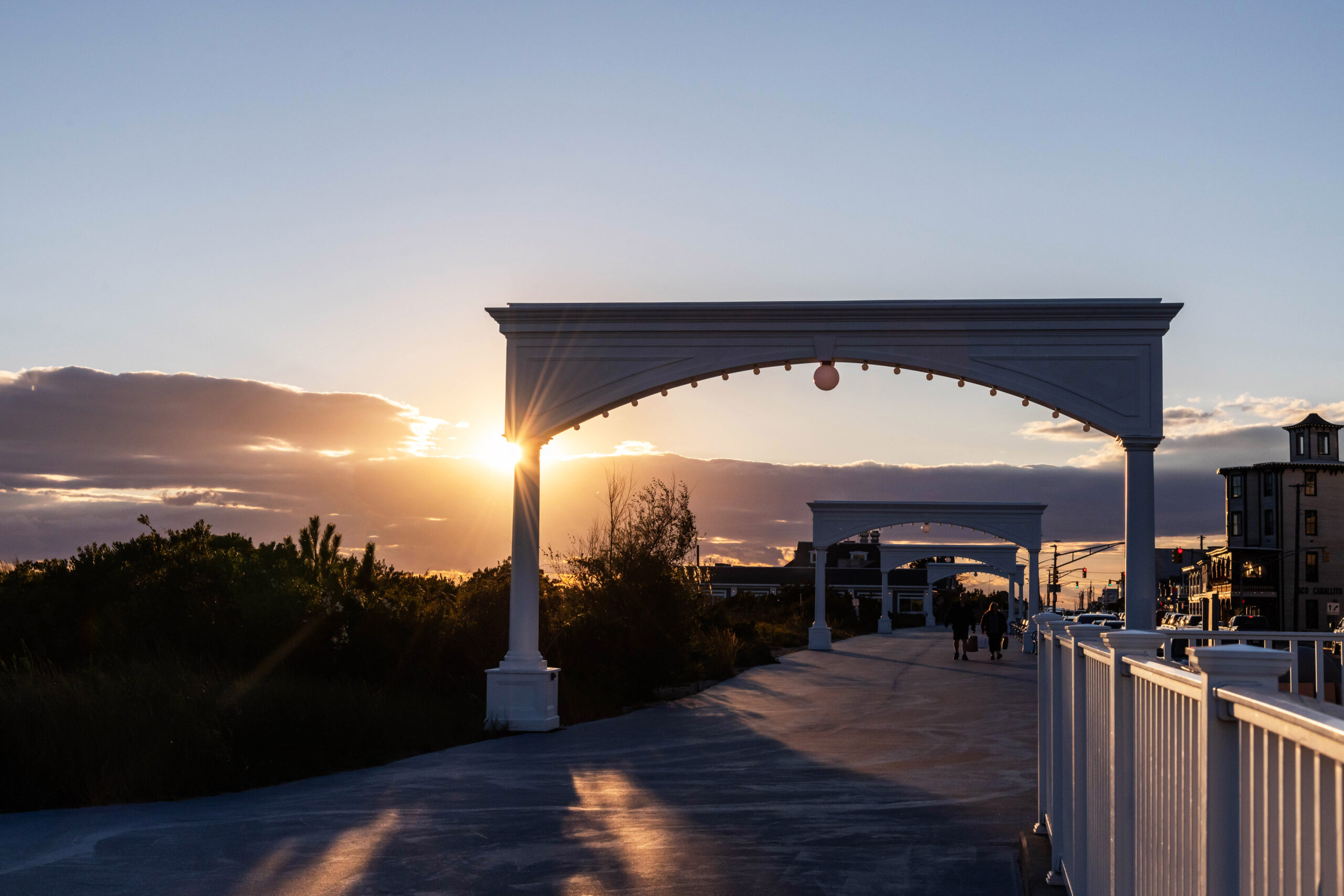 The sun setting behind the arches on the promenade with a few clouds in the sky