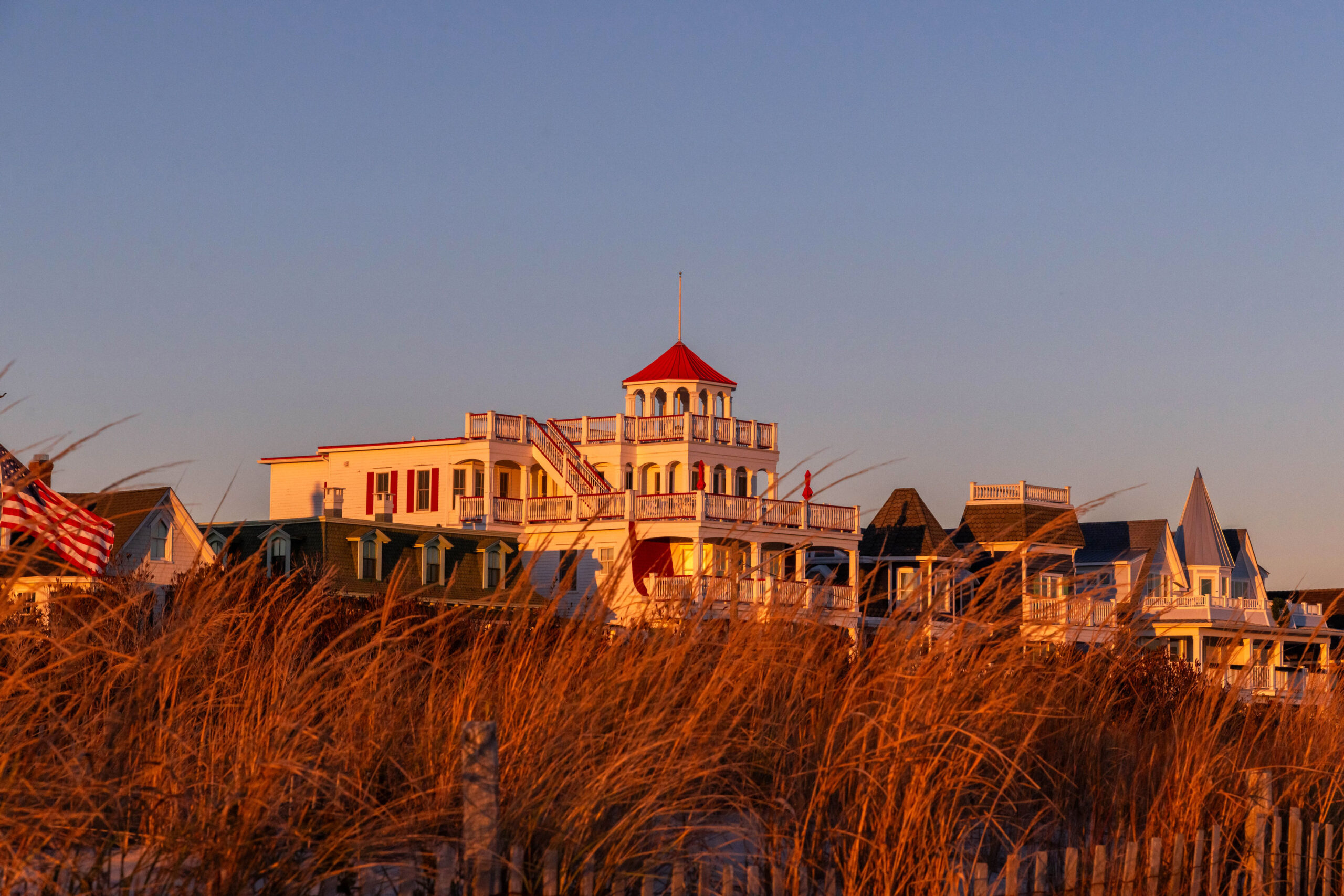 The sun shining on orange beach dunes and Victorian houses on Beach Ave.