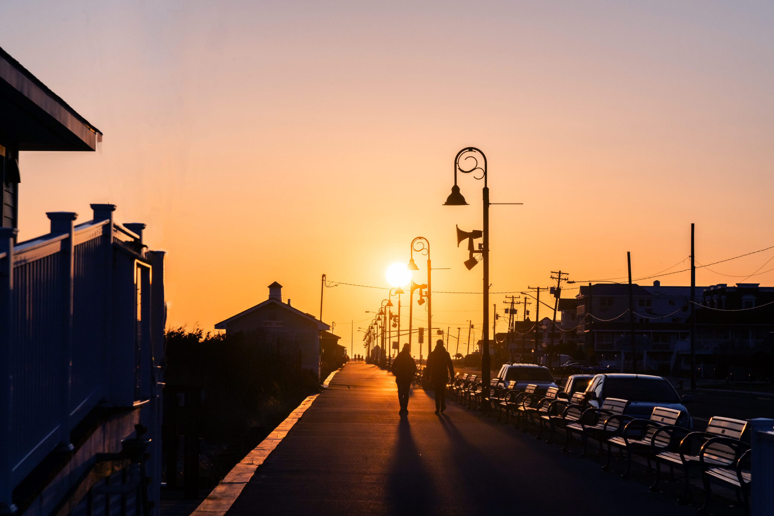 Two people walking on the promenade as the sun sets with a clear sky.