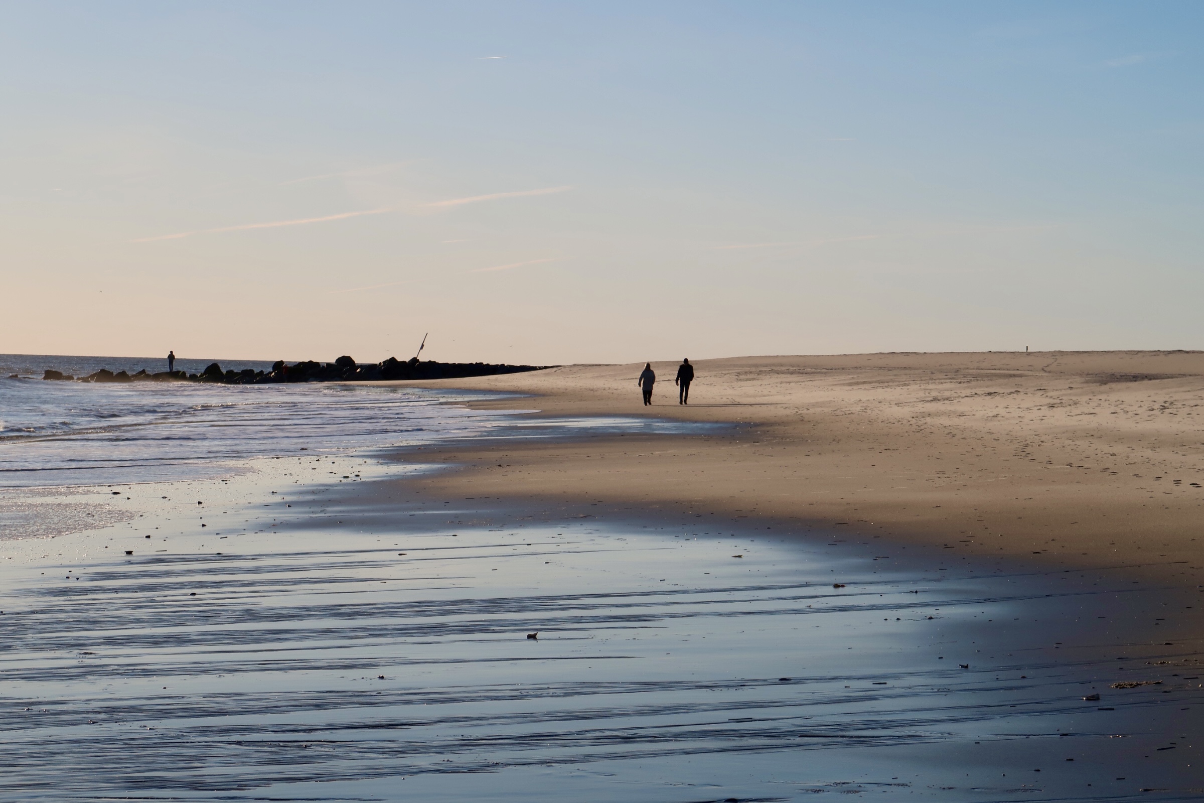 two people walking on the beach