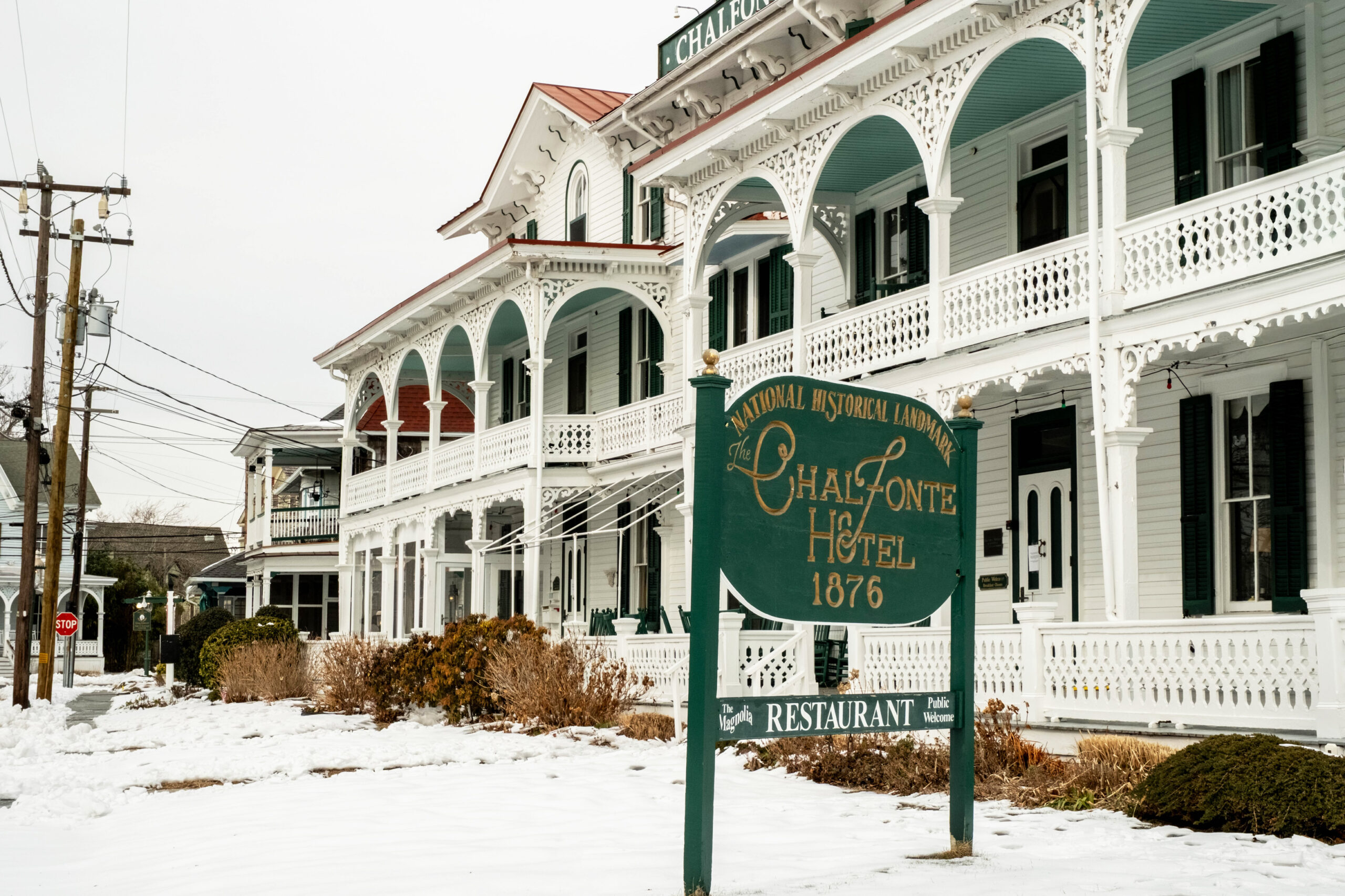 A wide view of The Chalfonte Hotel and sign on the front lawn, with snow on the ground and a cloudy gray sky.